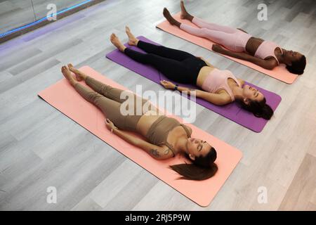 Diverse group of young women practicing shavasana after finishing yoga practice Stock Photo