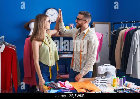 Man and woman tailors high five with hands raised up at clothing factory Stock Photo