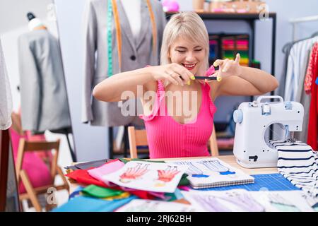 Young blonde woman tailor make photo by smartphone to clothing design at gaming room Stock Photo
