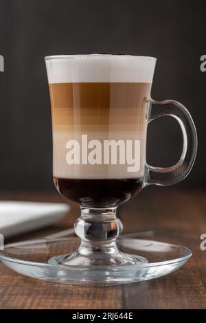 Multilayer coffee latte in glass cup on wooden table Stock Photo