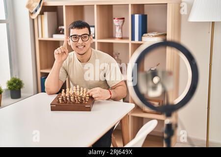 Young arab man doing chess tutorial smiling with an idea or question pointing finger with happy face, number one Stock Photo