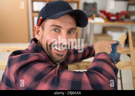 happy workman cutting wooden planks in workshop Stock Photo