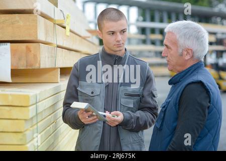 Salesman showing calculation to man in materials yard Stock Photo