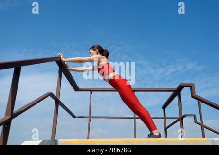 Fit, sporty woman doing stretching and push up exercises outside. Outdoor fitness concept. Stock Photo