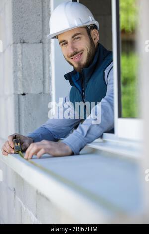 man worker in protective before installing sill on external window Stock Photo