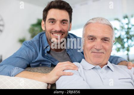 cheerful 60s father embrace grown up son Stock Photo