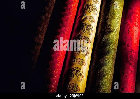 Close-up of a vibrant, multicolored fabric arranged in a neat pattern against a dark background Stock Photo