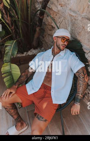 A young man with tattoos posing and enjoying the sunny weather on a hot summer day Stock Photo