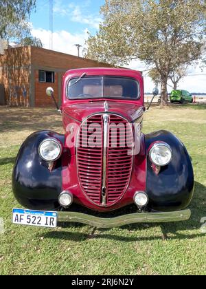 Old red and black utility pickup truck Ford 85 V8 1938 - 1939 on the lawn. Nature grass and trees. CAACMACH 2023 classic car show. Stock Photo