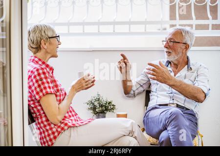 Senior couple sitting and talking on terrace at their home. Leisure time. Stock Photo