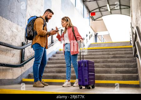 Adult couple missed the departure of the train. The are arguing at at the train station. Stock Photo