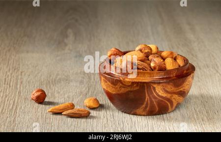 Mix of nuts hazelnuts and almonds in a wooden cup close-up. Stock Photo