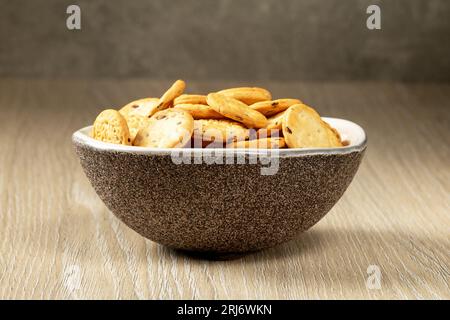 Brown porcelain cup with salted crackers on a wooden table.Close up Stock Photo