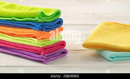Stack of kitchen microfiber towels in bright colors on a white wooden background. Stock Photo