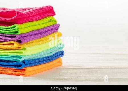 Stack of kitchen microfiber towels in bright colors on a white wooden background. Stock Photo