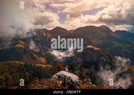 A scenic landscape featuring majestic mountains in the background, with a few wispy clouds drifting in front of them Stock Photo