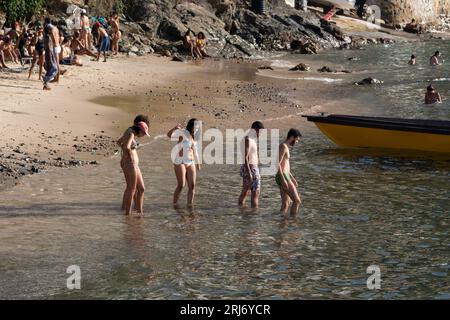 Salvador, Bahia, Brazil - January 14, 2022: People are seen bathing in the sea and sunbathing on the sands of the beach in the Gamboa community in Sal Stock Photo