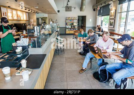 Augusta Georgia,Starbucks Coffee,inside interior indoors,barista preparing orders,customers using laptops working,man men male,adult,residents,inside Stock Photo