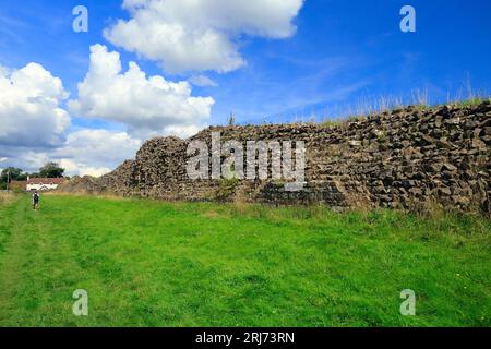 Walker on path alongside well preserved and impressive Roman walls surrounding Venta Silurum, a Roman settlement, Caerwent village, South Wales. Stock Photo