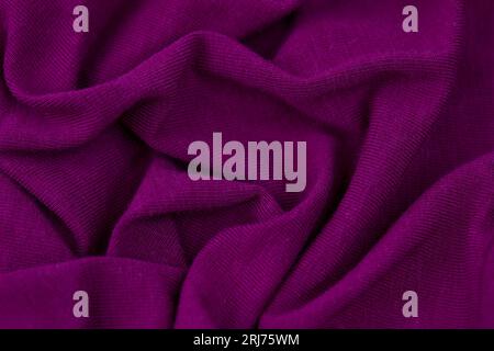 A close up shot of a cotton fabric in a vibrant purple hue, featuring a subtle, lightly-colored image Stock Photo