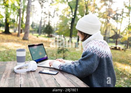Freelancer working on laptop in autumn park. Stock Photo
