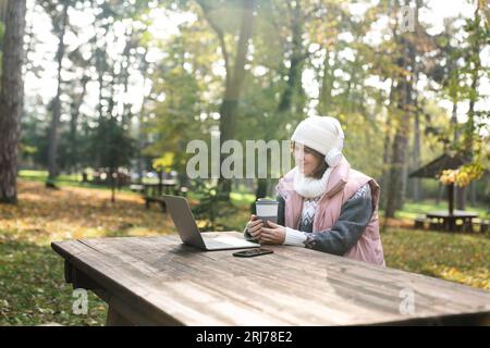 Freelancer working on laptop in autumn park. Stock Photo
