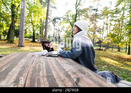 Freelancer working on laptop in autumn park. Stock Photo