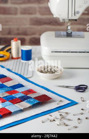 Quilt sandwich, curved basting pins, sewing machine and sewing accessories Stock Photo