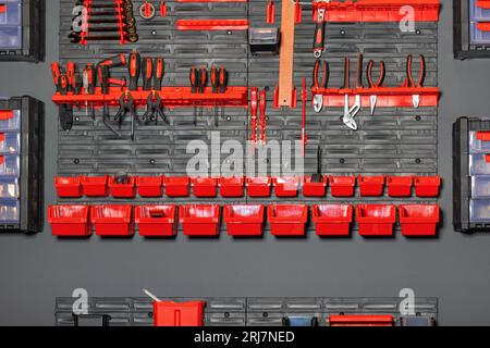 Various tools for diy and repair work in the workshop are organized in a wall stand with different drawers and organizers. Stock Photo