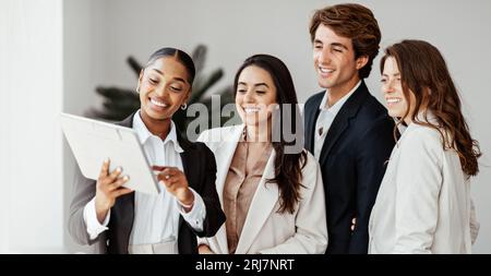 Digitizing business discussions. Team of multiracial colleagues using digital tablet during meeting in office, panorama Stock Photo