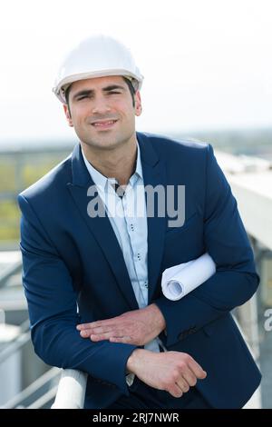portrait of suited man holding rolled up papers under arm Stock Photo