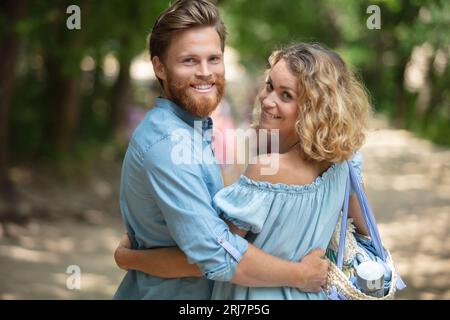 couple smiling and cuddling on a sunny day in park Stock Photo