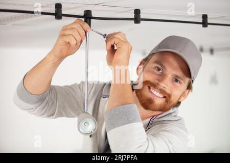 young electrician repairing ceiling light Stock Photo