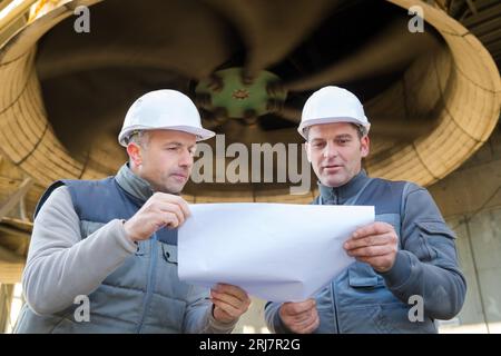 workers discussing paperwork on construction site Stock Photo