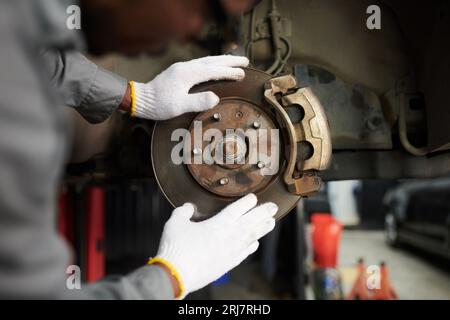 Closeup image of mechanic wearing textile gloves when checking car disc break Stock Photo