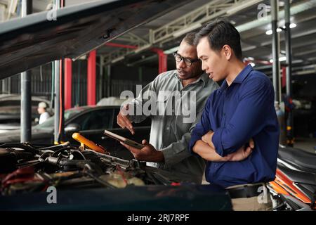Mechanic showing client results of car diagnostics on tablet computer Stock Photo