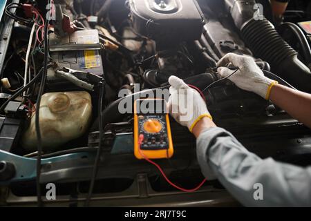 Car service worker using multimeter when checking car engine Stock Photo
