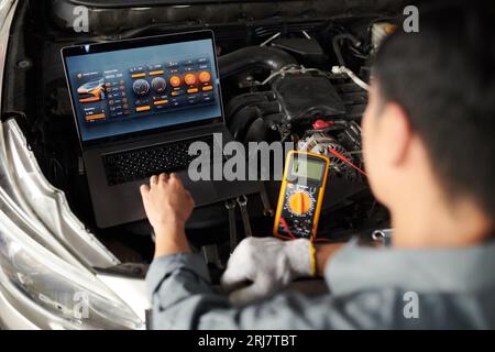 Car service worker using program on laptop when analyzing vehicle computer systems and components Stock Photo