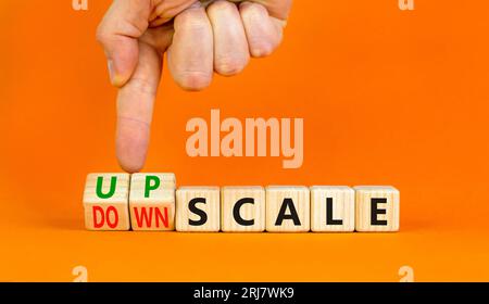 Upscale or downscale symbol. Concept words Upscale or Downscale on wooden cubes. Beautiful orange table orange background. Businessman hand. Business Stock Photo