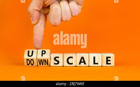 Upscale or downscale symbol. Concept words Upscale or Downscale on wooden cubes. Beautiful orange table orange background. Businessman hand. Business Stock Photo