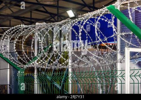 Fragment of the protective system for the protection of the perimeter of the territory with a metal fence and barbed wire. Stock Photo