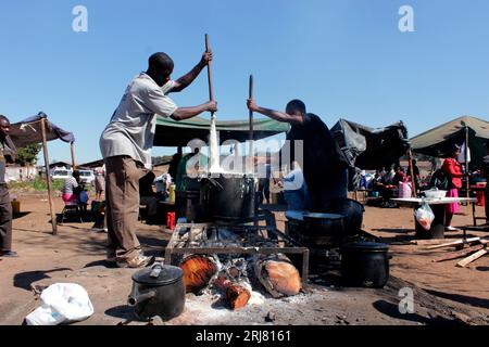 Two men are preparing sadza on a open fire at a open market in Mbare, Harare opposite Mupedzanhamo market. Most traders at the market get their food from the open food market. Zimbabwe. Stock Photo