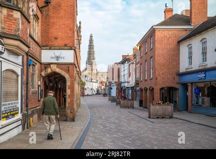 An elderly man walks down Conduit Street at sunrise with a view of Lichfield Cathedral, with its main spire being restored, in the distance in this an Stock Photo