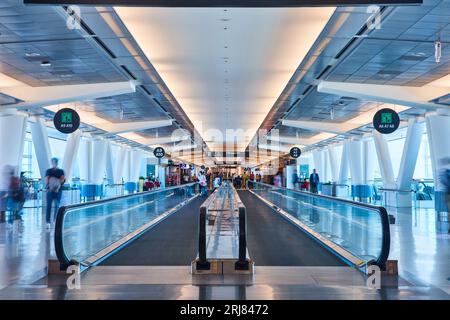 Two moving walkways side by side with people stepping on far end in airport Stock Photo