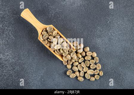 A wooden spoon filled with green coffee beans, top view Stock Photo
