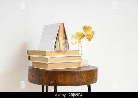 Stack of books with decor on table near light wall Stock Photo
