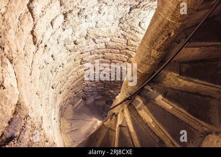 Old spiral staircase made with stone and with metal railing Stock Photo