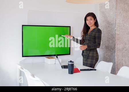 Smiling female worker showing empty screen in meeting room Stock Photo