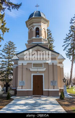 A picture of a majestic church with a wooden door and a tall bell tower situated in a lush park Stock Photo