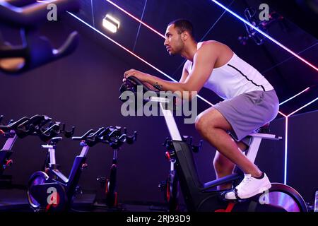 Young man training on exercise bike in fitness club Stock Photo